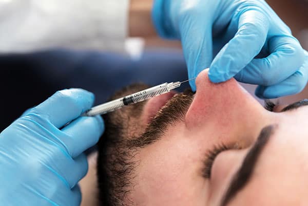 Man receiving liquid rhinoplasty injection, non surgical nose job.